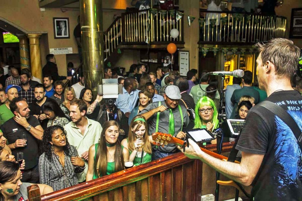 A group of people watching a band in The Dubliner on St Patrick's day.
